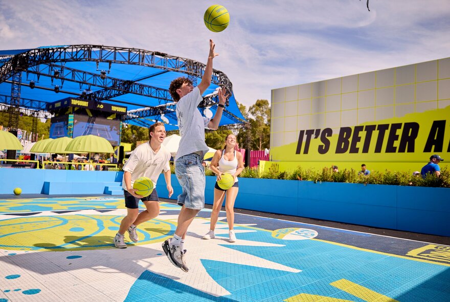 Kids playing on an outdoor court at the Australian Open with an oversized tennis ball. 
