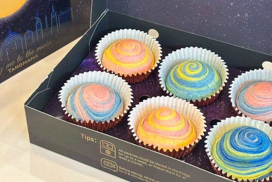 Six small rainbow coloured cupcakes in a gift box. 