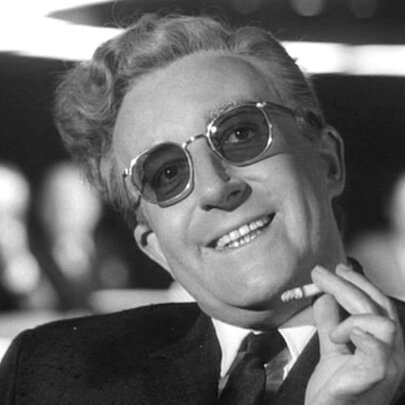 Peter Sellars smiling with a cigarette in hand in a black and white still image from the film Dr Strangelove.