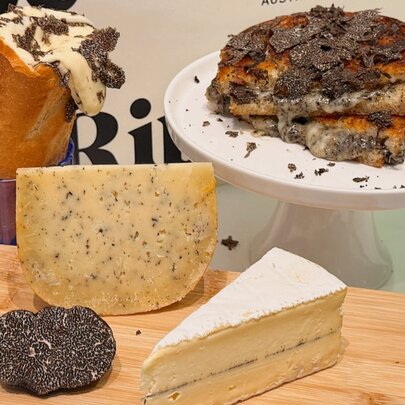 Selection of hard and soft cheeses, toastie and baguette on a plate and board.