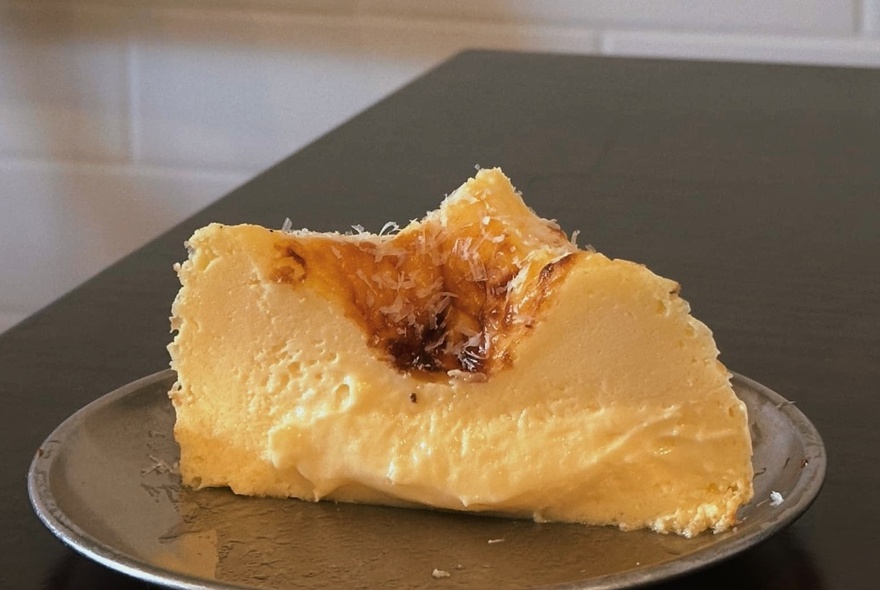 A gooey-centred Japanese-style cheesecake slice with a dip in the middle on a plate.