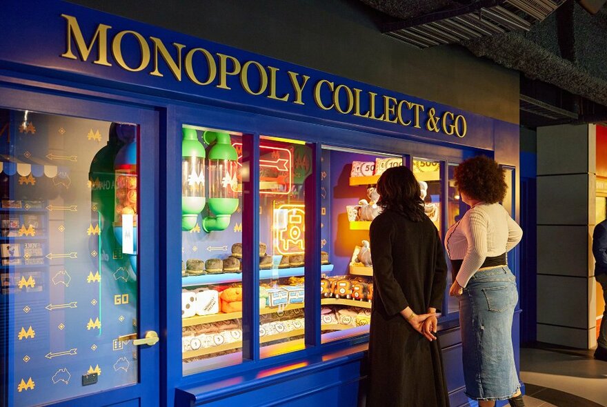 Two friends looking at a display of old Monopoly products.