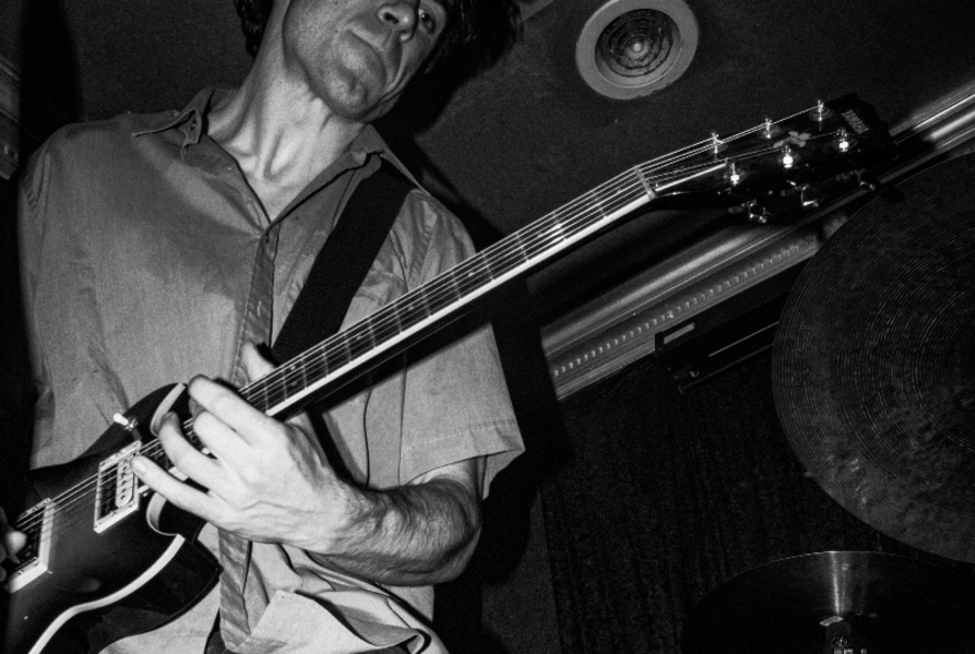 Musician playing a guitar in a dark venue.