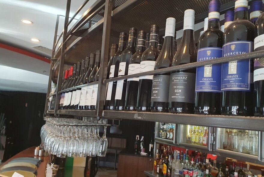 A bar shelf stocked with red wine. 