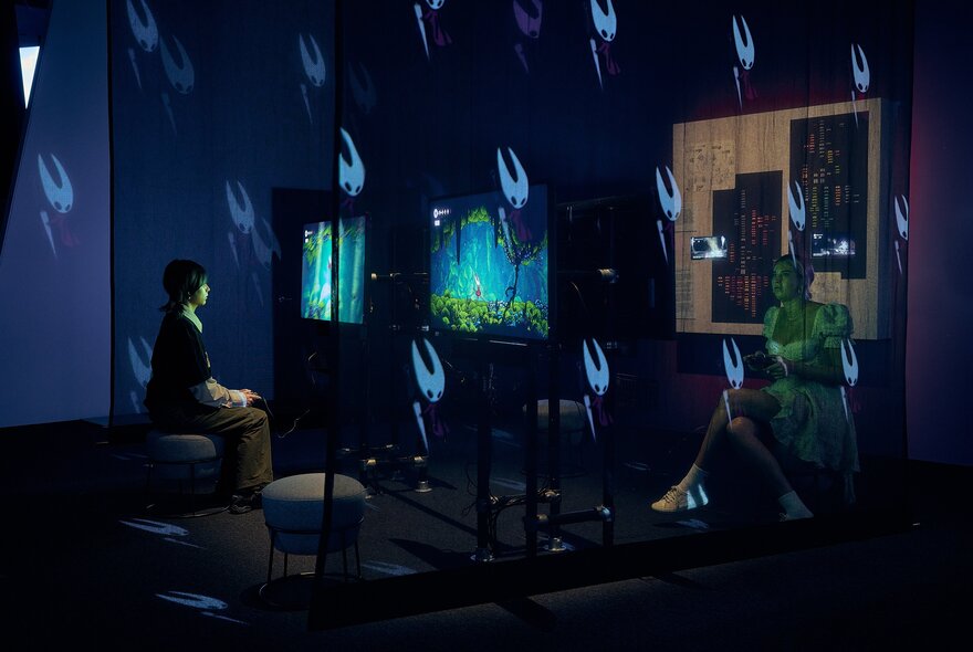 Person seated in a purple-lit dark room with screens and strange white flashes.