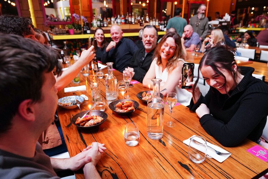 A large table of people all enjoying each other's company, laughing and interacting. 