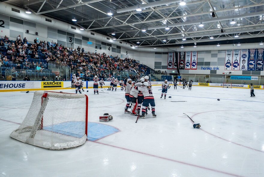 Ice hockey stadium with seated crowd and players during a game on the ice.