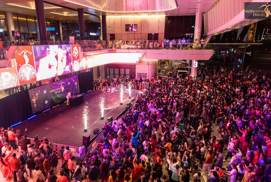 A stage at Marvel Stadium lit up with fireworks with a large crowd in front of it.