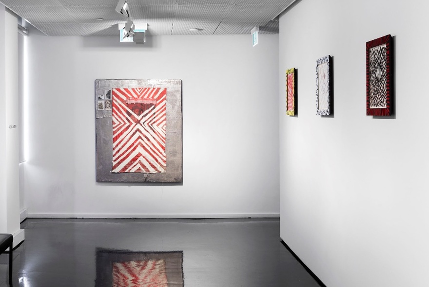 Paintings hanging on the white walls of a gallery.