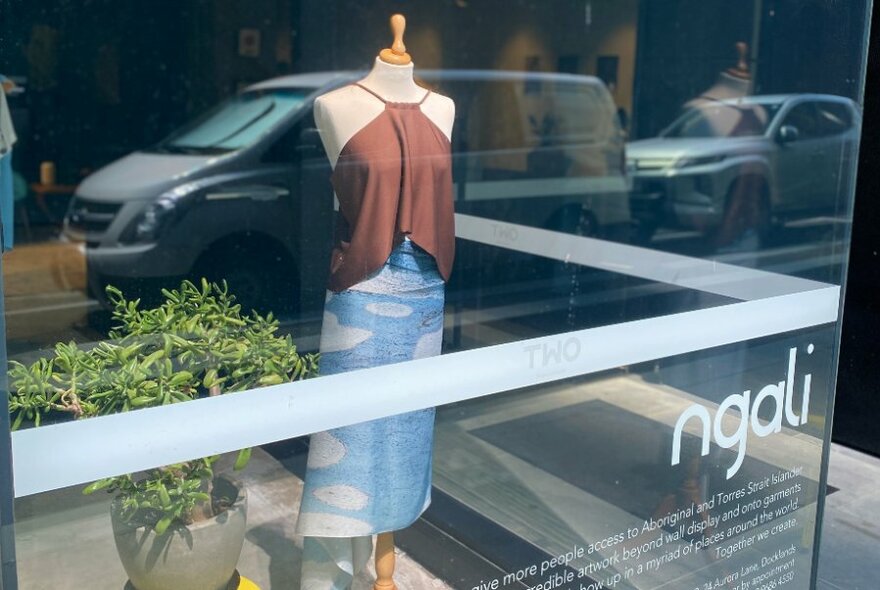 Exterior of the retail outlet Ngali, with a clothed mannequin and a green pot plant in the front window display.