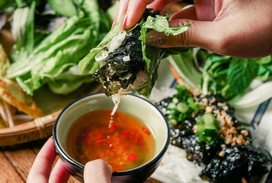 A Vietnamese snack being dipped into sauce.