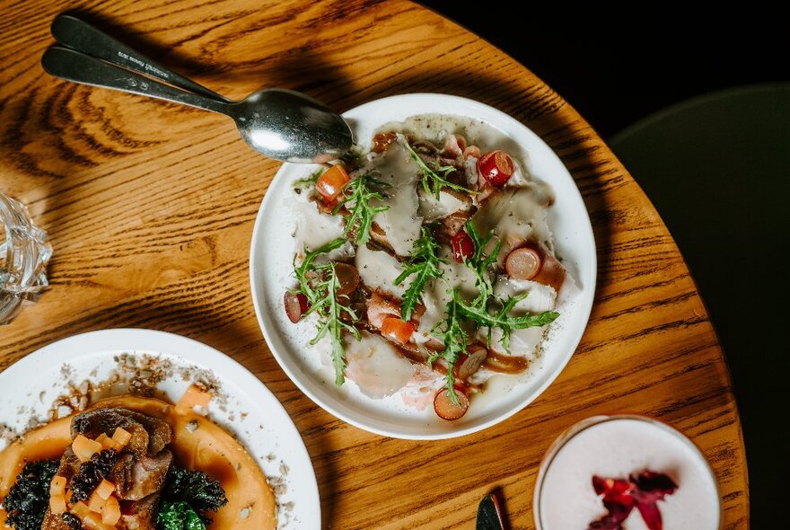 Three plates of food on a round wooden table.