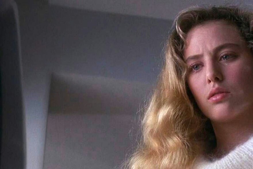 Scene from the film Electric Dreams with actress Virginia Madsen looking down with a puzzled expression.