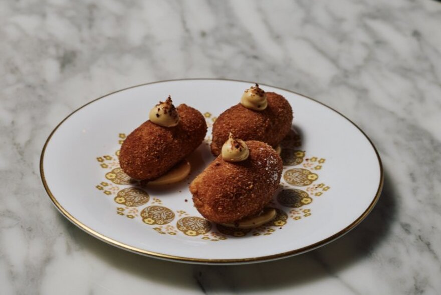 Plate of fried Portuguese croquettes with mayonnaise garnish.