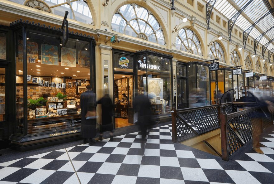 The art deco interior of the Royal Arcade in Melbourne, with black and white tiled floors and arched windows.