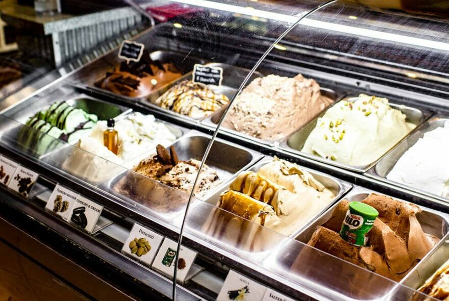 Tubs of ice-cream behind a plastic shield at a gelateria