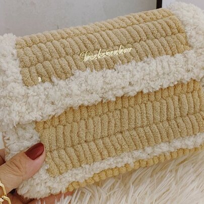 A beige and white knitted shoulder bag with plush trim and a chain strap, made in a cross-stitch workshop.