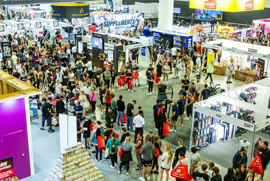 Looking down at a busy expo space with partitioned stalls and people queuing. 