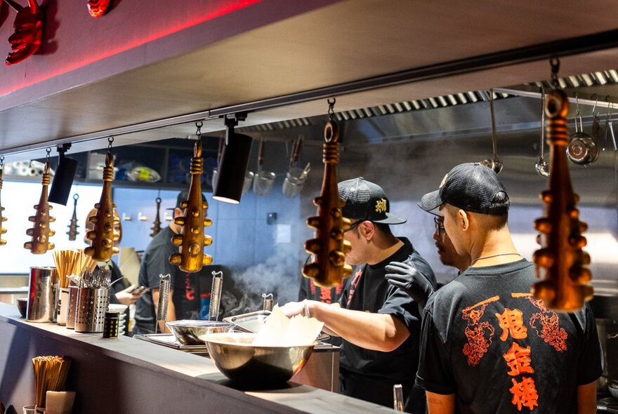 Cooks working in the busy kitchen of a ramen restaurant.