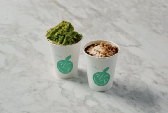 Matcha and regular hot chocolate takeaway drinks on a marble counter.