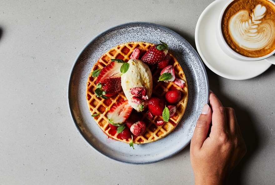 Waffle with strawberries and a cup of coffee.