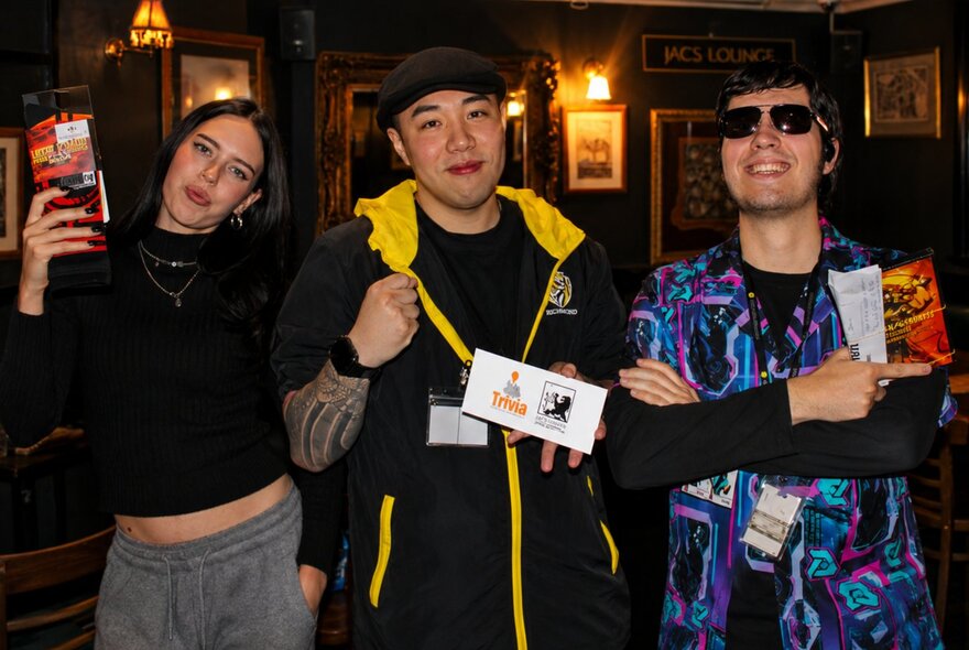 Gamers holding certificates in a bar area with wall lighting.