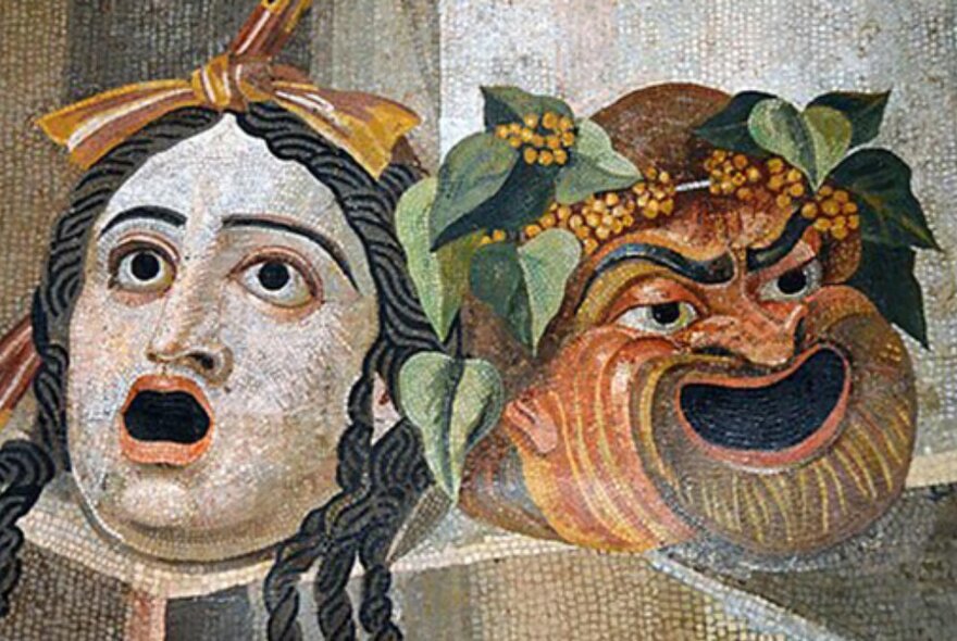 Ancient Roman wall mosaic of two theatrical masks depicting comedy and tragedy.