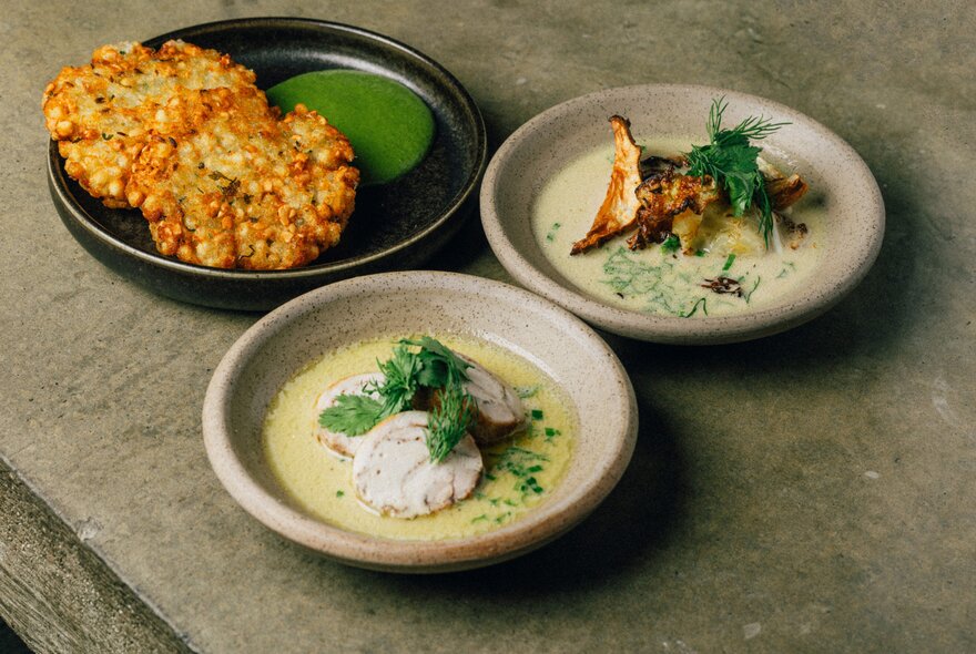 Three small plates of restaurant food with garnishes. 