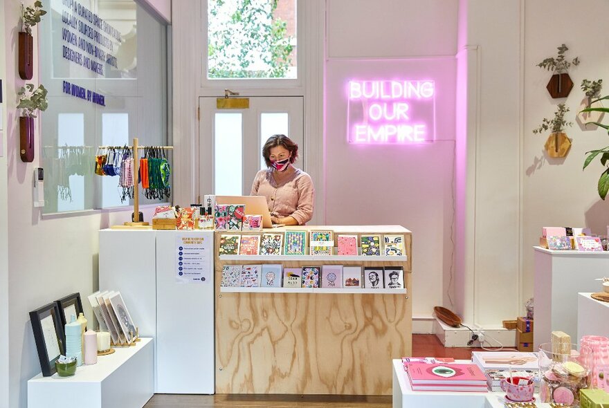 A shop clerk is standing behind a counter at a gift shop