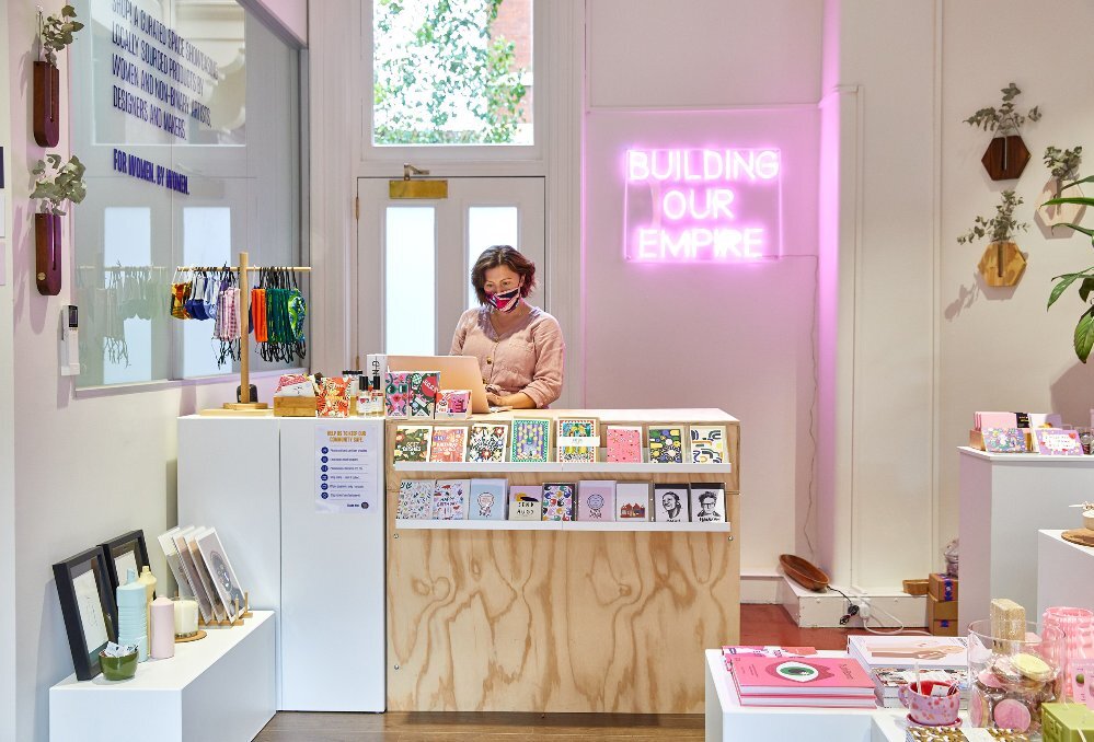 A shop clerk is standing behind a counter at a gift shop