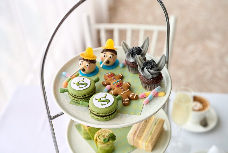 A multi-tiered high tea service featuring finger sandwiches, pastries, and sweets inspired by characters from the movie Shrek.