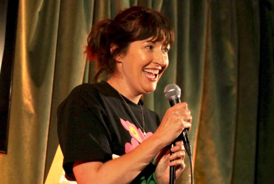 Stand up comedian Celia Pacquola talking into a microphone on stage.