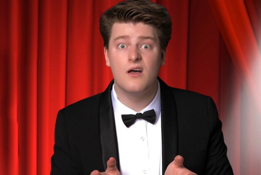 Magician / comedian LJ looking puzzled with his lip curled in a tuxedo. 