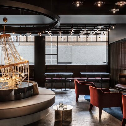 Lobby of Lancemore Crossley St hotel, with a lounge area featuring a large, circular banquette as a focal point with a caged chandelier centerpiece.