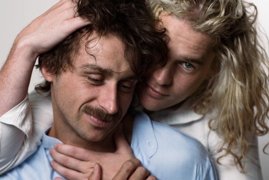 Two men embracing, one holding the other by head and neck from behind.