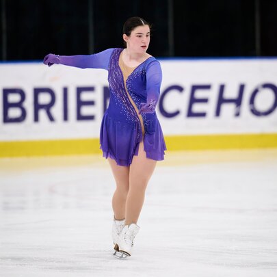 An ice skater in a purple dress on the O'Brien Icehouse rink. 