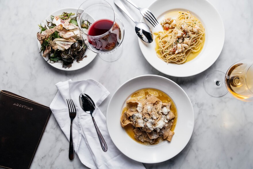 Aerial view of a table with plates of pasta and glasses of wine.