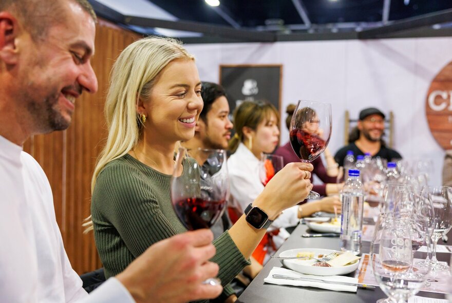 People at a wine tasting all smiling and trying red wine. 