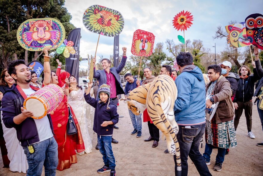 Festivalgoers holding tiger-themed items, flags and signs.