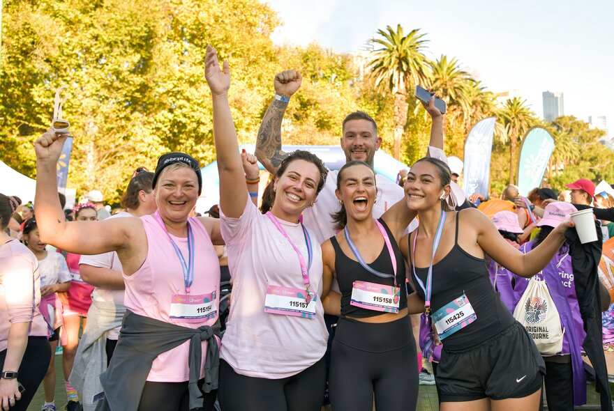 A group of marathon runners in a park posing and looking happy. 