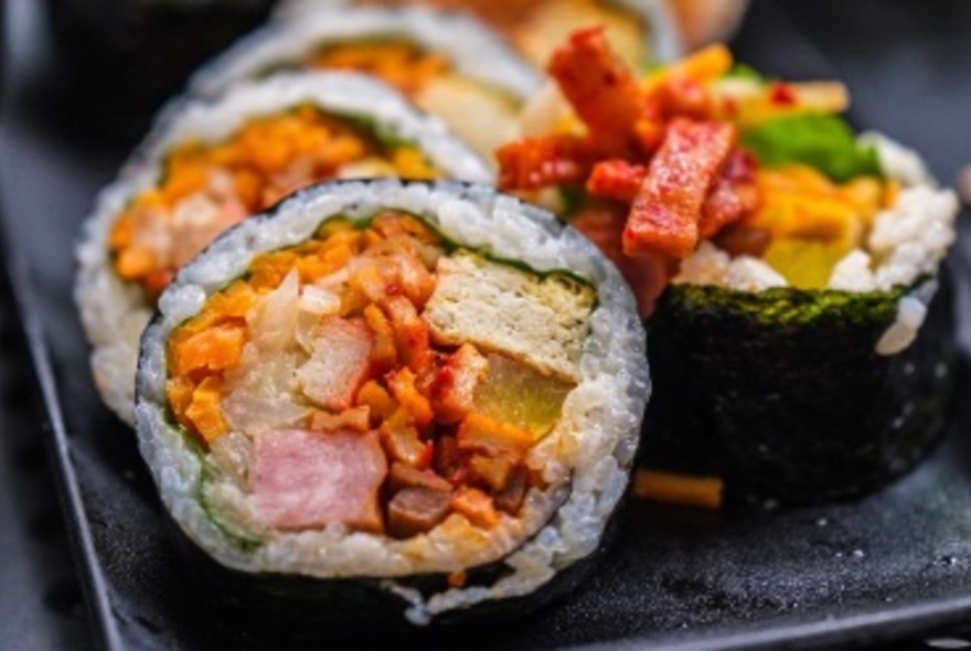 Korean sliced gimbap – rice with fillings wrapped in seaweed, similar to Japanese sushi – presented on a black platter.