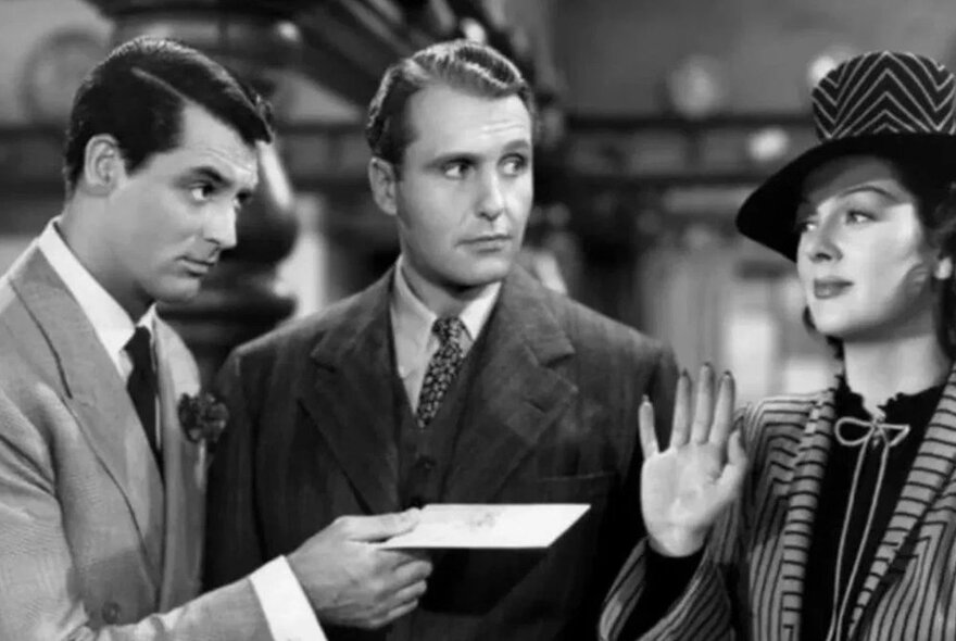 Black and white film still of two men and a woman, dressed in clothes from the 1950s.