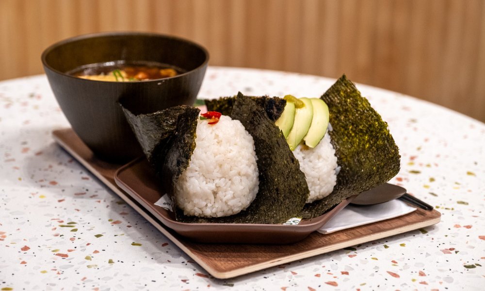 Wooden tray with two onigiri and a soup.