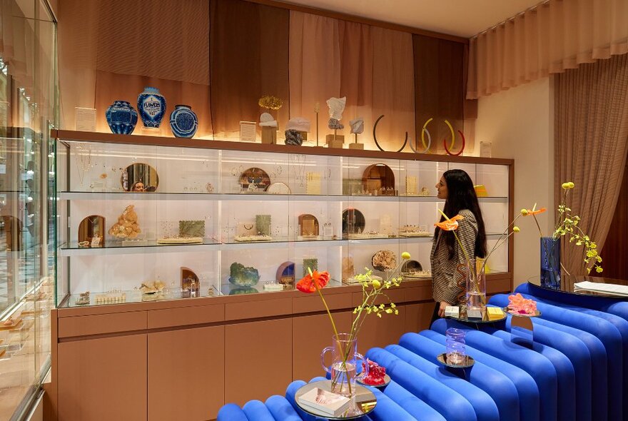 A woman browsing in a jewellery store with a floral art installation.
