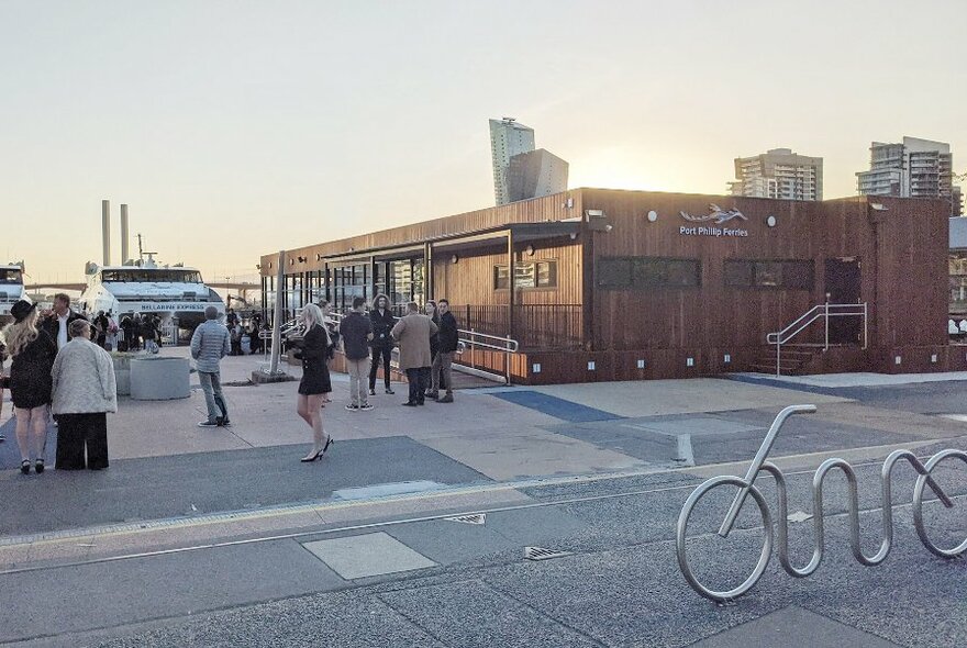 Ferry terminal building with people queueing and ferry at dock.