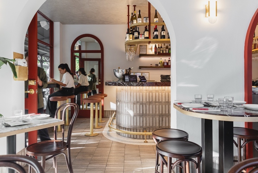 The interior of D.O.C Osteria, an Italian restaurant in Carlton, with tables, stools and archways leading through to the bar.