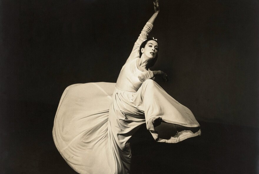 A black and white photograph of a young woman dancing, with her wide skirt swirling around her legs.