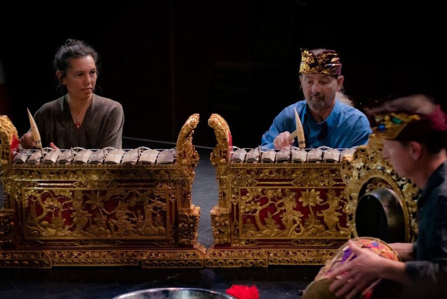 Gamelan players sitting on stage performing. 