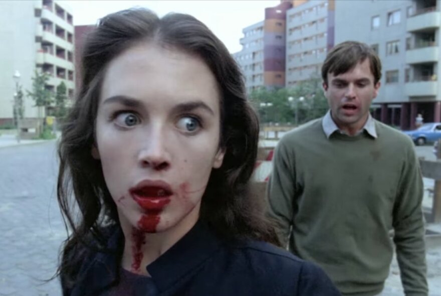 Actress Isabelle Adjani with blood on her face, alongside actor Sam Neill in a tense scene from the psychological horror film Possession.