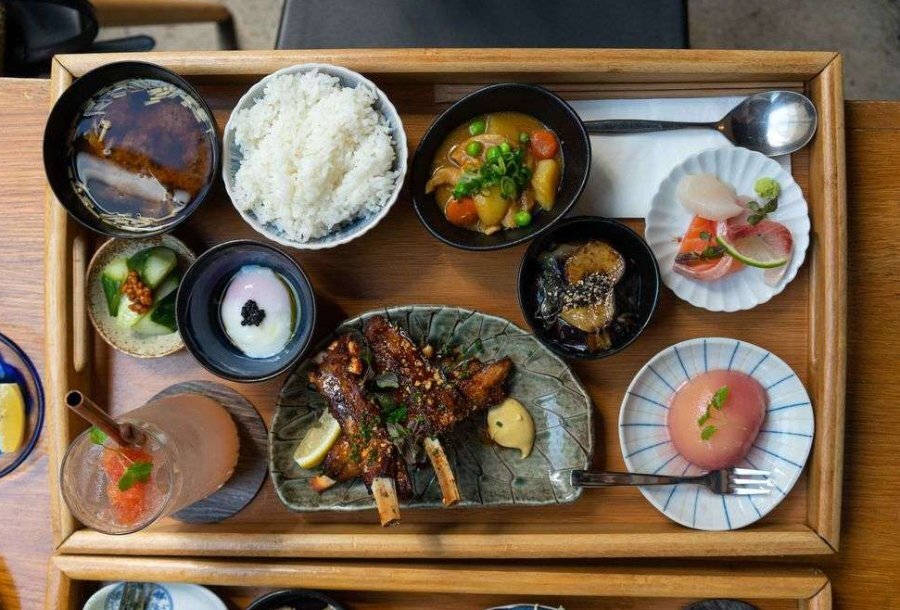 A wooden serving board plated with Japanese food.